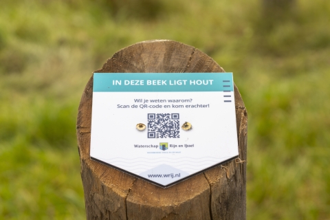 de beekhoutpaal in Winterswijk met een QR-bordje voor meer informatie over het hout in de beek