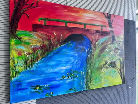 Een kleurrijk kunstwerk van een brug aan de muur in het kantoor