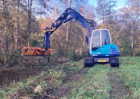 Kraan met maaibalk. De kraan heeft ruspbanden. Zelfs met deze banden maakt hij sporen in de grond.