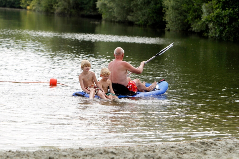 opa met kleinkinderen in rubber bootje in een zwemplas