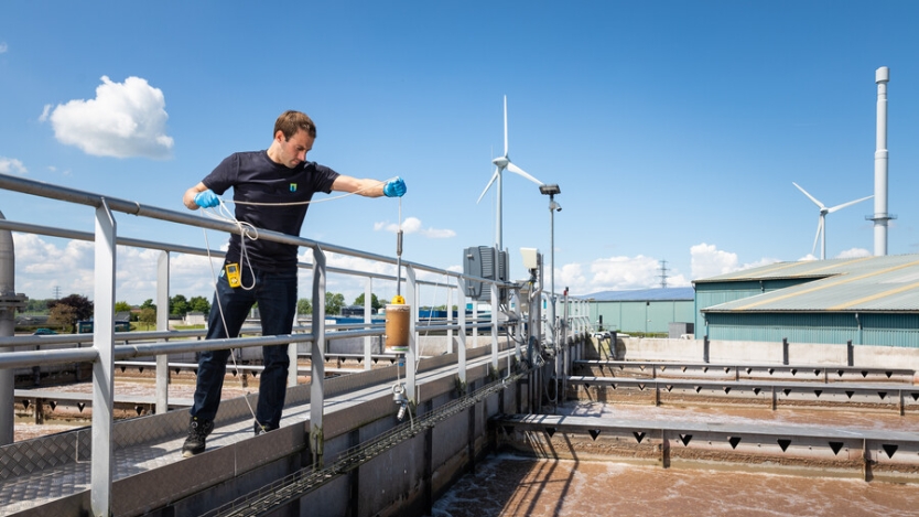 Medewerker waterschap is aan het meten in een (riool-)waterzuivering waar ook windenergie wordt opgewektWindenergie op